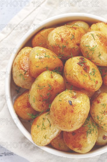 Baked new potatoes, with butter and dill, on a white plate, at home, no people
