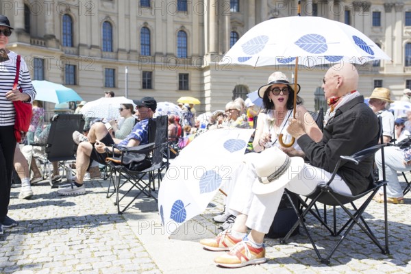 Two visitors under a parasol at the Staatsoper fÃ¼r alle, a free open-air concert with conductor Christian Thielemann and the Staatskapelle Berlin on Berlin's Bebelplatz, Berlin, 22 June 2025