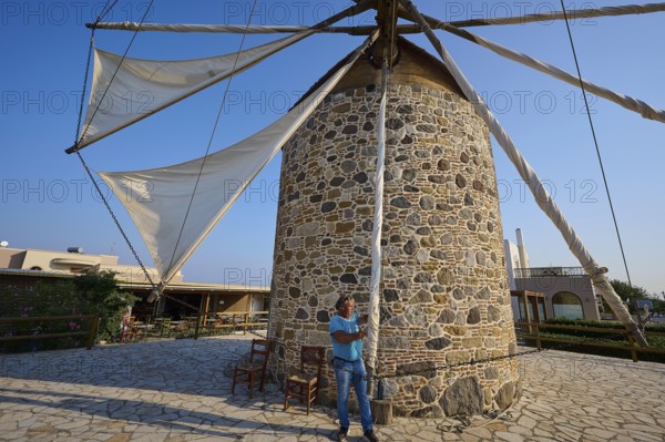 Stone mill with sails, a man pulling a rope under a blue sky, windmill, Antimacheia, Kos, Dodecanese, Greek Islands, Greece
