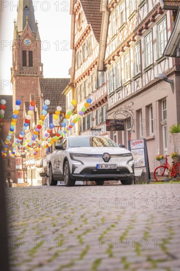 A car on a cobbled street with half-timbered houses and balloons, Deer E, car sharing, electric car, Calw, Black Forest