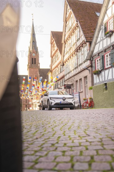 A car drives through a historic town with half-timbered houses and balloons, Deer E, car sharing, electric car, Calw, Black Forest