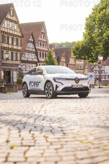 A white car parked on a cobbled square with charming half-timbered houses in the background, Deer E, car sharing, electric car, Calw, Black Forest