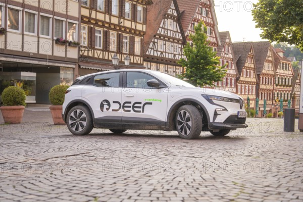 White car on a cobbled street in an old town with half-timbered houses in the background, Deer E, car sharing, electric car, Calw, Black Forest