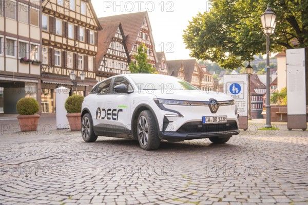 White car on a cobbled street in a historic town centre with half-timbered houses, Deer E, car sharing, electric car, Calw, Black Forest
