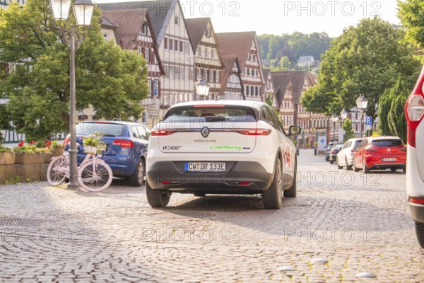 Car on a cobbled street with a view of other parked cars and half-timbered houses in the background, Deer E, car sharing, electric car, Calw, Black Forest