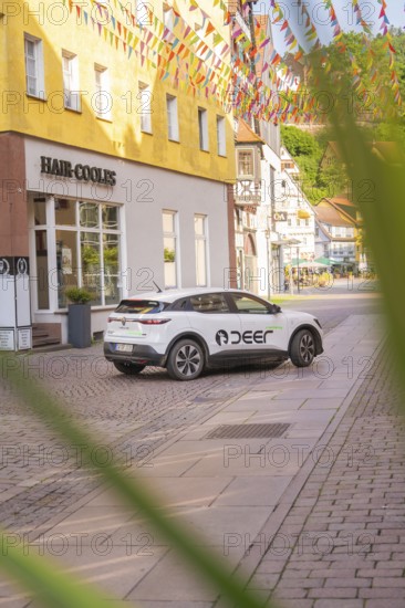 A car parked on a cobbled street with colourful houses, Deer E, car sharing, electric car, Calw, Black Forest
