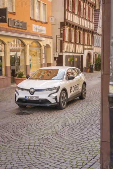 An electric car in front of half-timbered houses in a historic shopping street, Deer E, car sharing, electric car, Calw, Black Forest