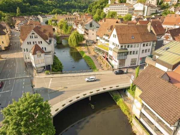 Aerial view of a town with a river and bridge, showing half-timbered buildings and green trees from a bird's eye view, Deer E, car sharing, electric car, Calw, Black Forest