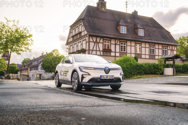 An electric car in an old town centre with a historic building in the background, streets wet, Deer E, car sharing, electric car, Calw, Black Forest