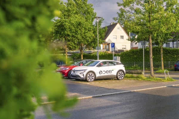 An electric car parked in the sunset on a quiet street surrounded by trees, Deer E, car sharing, electric car, Calw, Black Forest