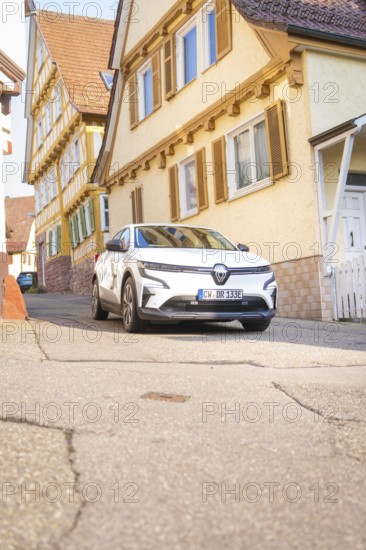 A white car drives down a traditional street with half-timbered houses, Deer E, car sharing, electric car, Calw, Black Forest