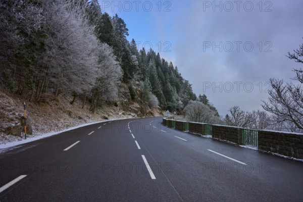 Snowy road snaking through a wintery forest with frost-covered trees, winter, Col de la Schlucht, Le Valtin, Vosges, France