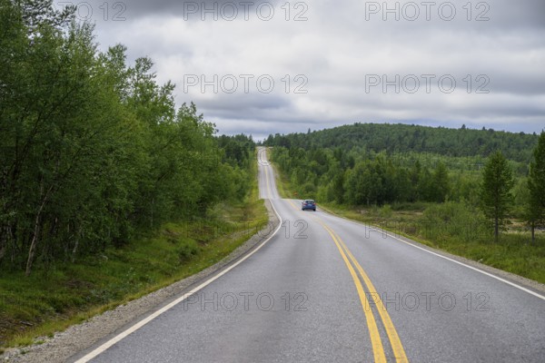 A lonely road leading through a green, wooded hilly landscape of Finland's countryside, Karelia, Lapland, Finland