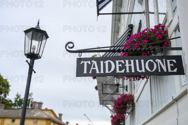 Street scene in the old town of Naantali, street view with lamp and hanging flowers in front of a building. Inscribed sign adds a cultural touch to the image, Naanatali, Varsinais-Suomi, Finland