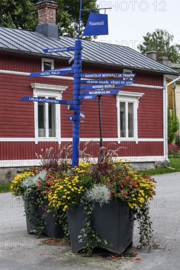Street scene in the old town of Naantali, colorful signposts and flowers in front of a red wooden house create a nostalgic Scandinavian atmosphere, Naanatali, Varsinais-Suomi, Finland