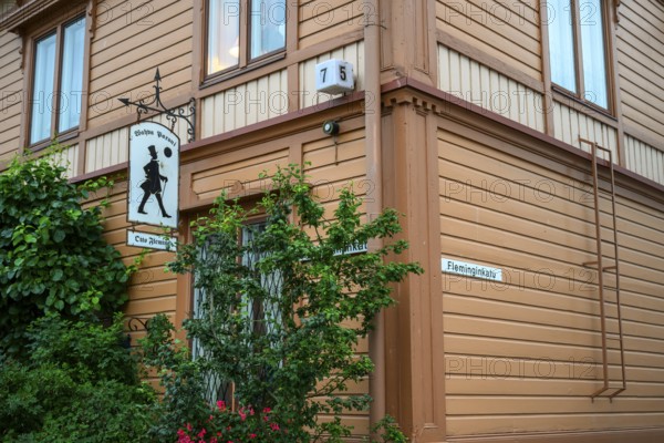 Street scene in the old town of Naantali, orange-painted wooden house with road signs and lush vegetation, on a quiet street, Naanatali, Varsinais-Suomi, Finland