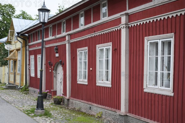 Street scene in the old town of Naantali, red historic wooden building with decorative windows on a paved street, Naanatali, Varsinais-Suomi, Finland