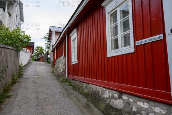 Street scene in the old town of Naantali, alley with red wooden buildings and white windows. A charming rustic townscape, Naanatali, Varsinais-Suomi, Finland