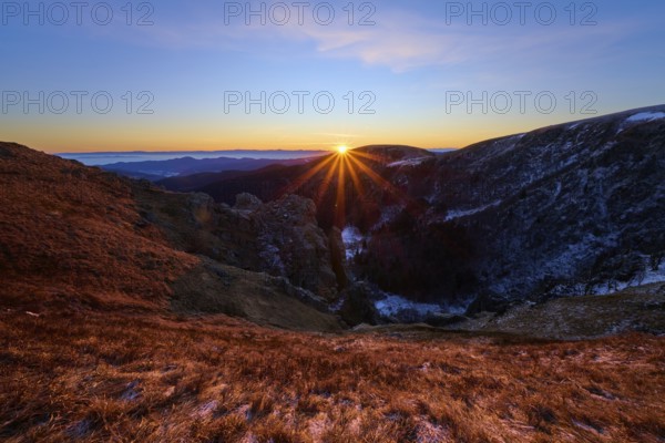 Sunbeams break over the mountains, orange sky and shades of blue, looking towards the Rhine Valley, Martinswand, Frankental, Vosges, France