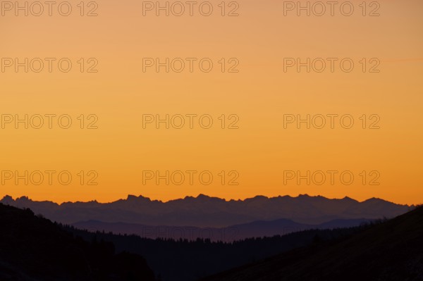 Mountain silhouette at sunrise with orange sky, looking at Alps, Hohneck, La Bresse, Vosges, France