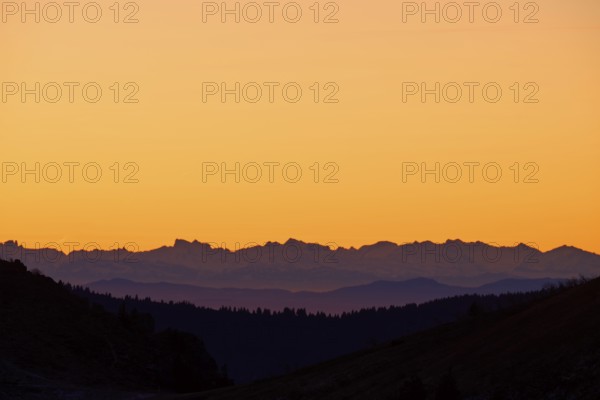 Silhouette of mountains at sunrise with orange sky, looking at Alps, Hohneck, La Bresse, Vosges, France