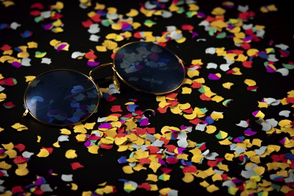 Sunglasses on colorful confetti against black background, Mardi Gras