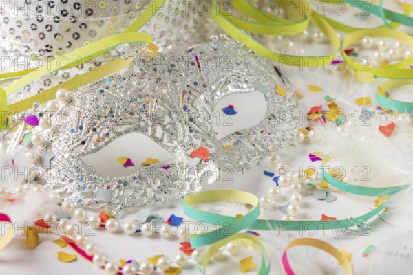 Silver carnival mask with pearls and colorful confetti on white background
