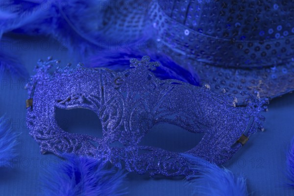 Blue mask with matching feathers and hat on blue background, carnival