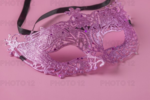 Glittering pink mask lying on a pink background