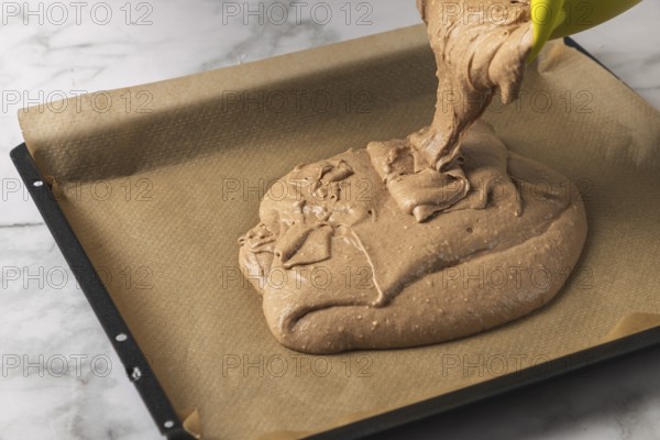 Cocoa dough is poured onto a baking sheet lined with baking paper
