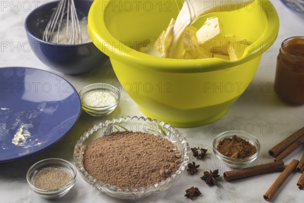 Milk is added to baking ingredients in dough bowls surrounded by cocoa, cinnamon, and other spices