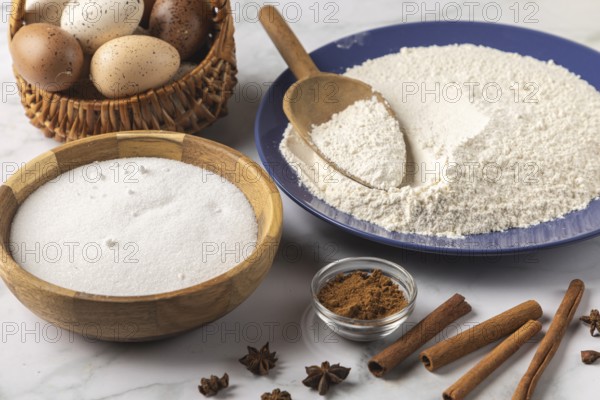 Baking ingredients such as flour, sugar, cinnamon and eggs on a table