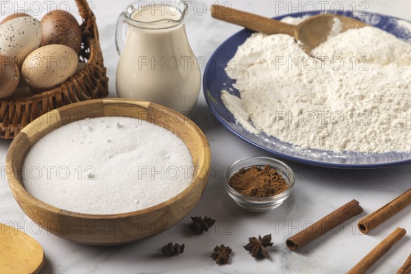 Baking ingredients, flour, sugar, cinnamon, milk and eggs on a table