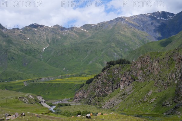 View of a green valley with a river surrounded by rocky and grassy mountains, Terek River, Kazbegi, Stepantsminda, Georgian Military Road, Mtskheta-Mtianeti Province, High Caucasus, Georgia