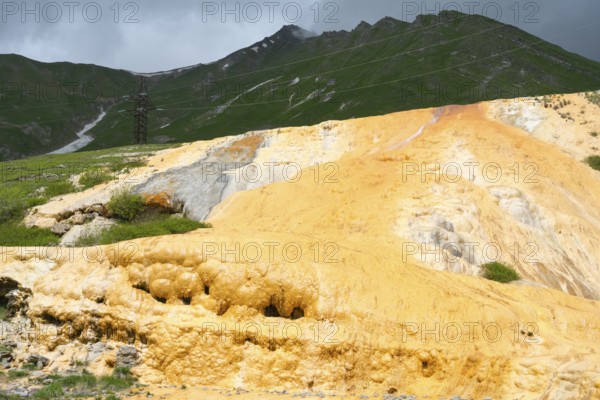 Yellow rocky landscape with green mountains and dark cloudy sky, Bidara Travertine, Travertine, Jvari Pass Trawertin Natural Monument, Cross Pass, Mtskheta-Mtianeti Province, Georgia