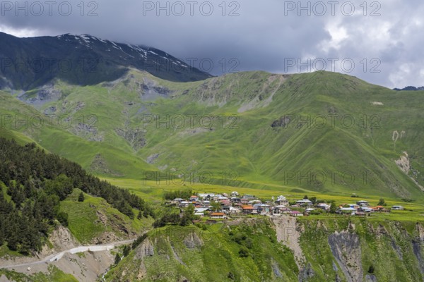 Mountain village in green hilly surroundings under a cloudy sky, dramatic landscape, view of Kanobi, Kazbegi, Stepantsminda region, Georgian military road, Mtskheta-Mtianeti province, High Caucasus, Georgia
