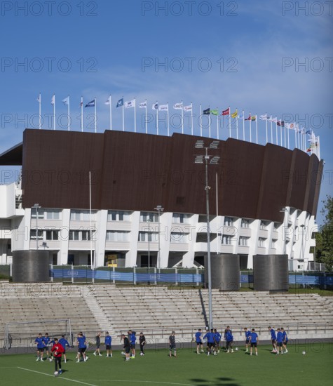 Football players train in front of Olympic Stadium or Finnish Olympic Stadium, architects Yrjö Lindegren and Toivo Jäntti, Helsinki, Finland