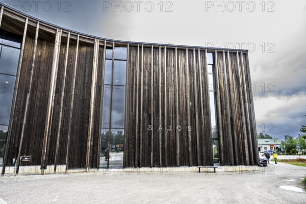 Detailed view of a modern wooden façade with large glass windows under a cloudy sky, Sámi Cultural Centre Sajos, Inari, Lapland, Finland