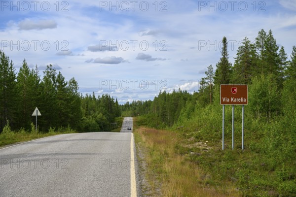 Via Karelia country road with a sign and surrounding trees under blue sky, Kuusamo, Lapland, Finland