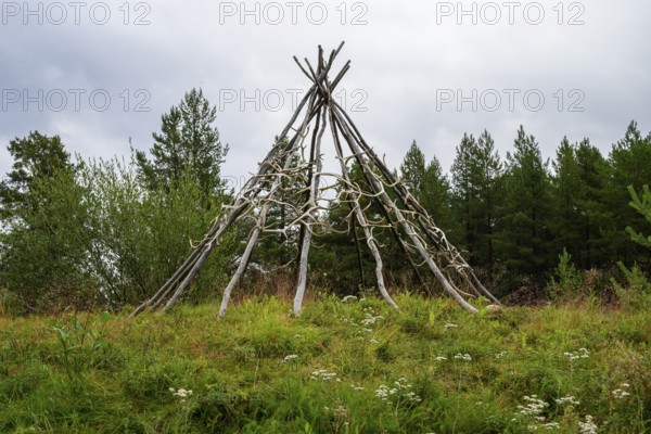 Rustic wooden structure made from birch trunks and reindeer antlers in a natural setting with trees and meadow in the background, Varangerbotn, Finnmark, Norway