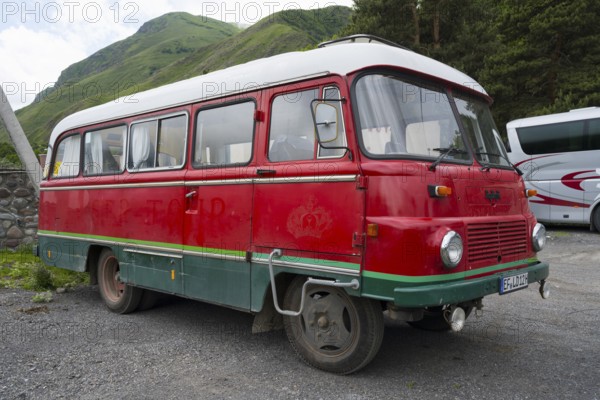 Old nostalgic bus in red with green accent on a parking lot in a mountainous landscape, vintage car, Robor LO 3000 bus from the GDR, Georgia