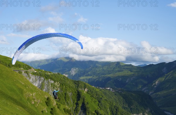 Paraglider flying with blue sky and mountain scenery, a sense of freedom and adventure, paraglider, paraglider near Gudauri, Mtskheta-Mtianeti region, Georgian Military Highway, High Caucasus, Georgia