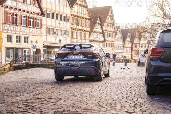 Car drives through a historic street surrounded by traditional half-timbered houses and cobblestones, MG4 electric car, Deer e-Carsharing, Calw, Germany