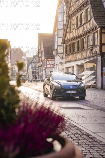 Black car in quiet old town with half-timbered houses and warm sunlight, MG4 electric car, Deer e-Carsharing, Calw, Germany