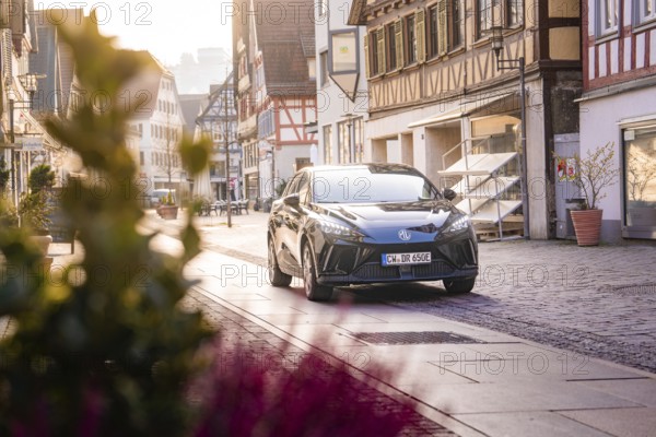Black car in a charming old town, flowers in the foreground, morning atmosphere, MG4 electric car, deer e-car sharing, Calw, Germany