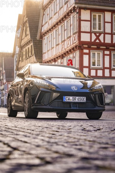 Black car in a half-timbered town, street view, morning light, MG4 electric car, deer e-car sharing, Calw, Germany