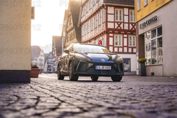 Black car in an almost empty cobblestone street in the old town, MG4 electric car, Deer e-Carsharing, Calw, Germany