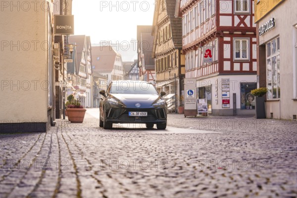 Black car in an old town with shops and cobblestone streets, MG4 electric car, deer e-car sharing, Calw, Germany