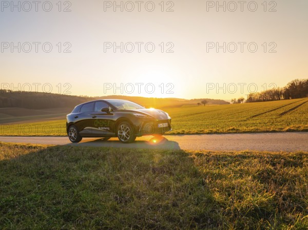 The car is parked on a country road at sunset, with wide fields dominating the scene, MG4 electric car, Deer e-Carsharing, Calw, Germany