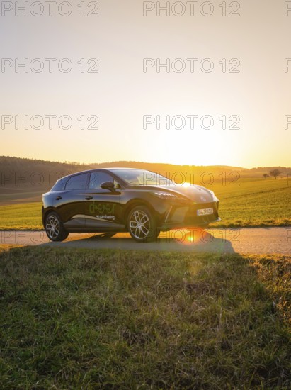 Black car parked on a country road surrounded by green fields when the sun is low, MG4 electric car, Deer e-Carsharing, Calw, Germany